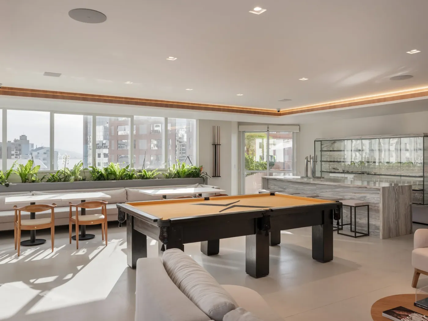 Lounge com mesa de sinuca e copa com bancada de mármore em escritório corporativo reformado pela C.A. Guimarães em Florianópolis